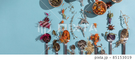 Assortment of dried relaxing tea herbs in spoons on blue background. Calendula, mint, anise hyssop, monarda didyma, wormwood, sage leaves. Assortment of dried relaxing tea herbs in spoons on blue background. Calendula, mint, anise hyssop, monarda didyma, wormwood, sage leaves. 85153019