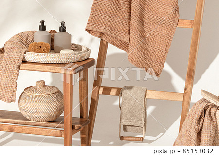 Natural waffle linen towels in earth tones on wood bench and towel ladder with bamboo toothbrushes, rattan baskets, and soap dispenser. Daily body care, spa and wellness zero waste bathroom concept Natural waffle linen towels in earth tones on wood bench and towel ladder with bamboo toothbrushes, rattan baskets, and soap dispenser. Daily body care, spa and wellness zero waste bathroom concept 85153032