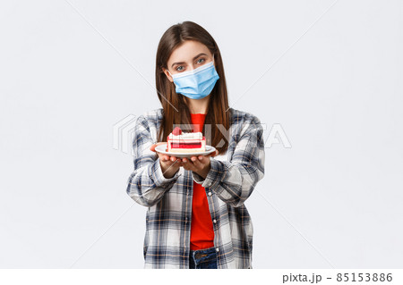 Coronavirus outbreak, lifestyle during social distancing and holidays celebration concept. Tender caring girlfriend made homemade cake, giving it to you, wear medical mask and smiling 85153886