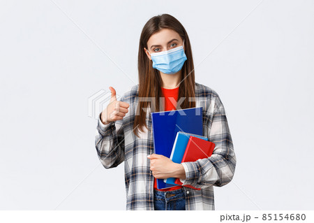 Coronavirus pandemic, covid-19 education, and back to school concept. Pleased young female freshman in college, showing thumb-up as studying prestige univeristy, carry notebooks Coronavirus pandemic, covid-19 education, and back to school concept. Pleased young female freshman in college, showing thumb-up as studying prestige univeristy, carry notebooks 85154680