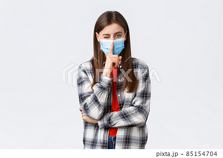 Coronavirus outbreak, leisure on quarantine, social distancing and emotions concept. Attractive young woman in checked casual shirt and medical mask ask keep secret, press finger to lips shush 85154704