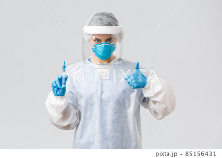 Covid-19, medical research, healthcare workers and quarantine concept. Confident professional doctor in personal protective equipment PPE costume, show thumb-up, hold syringe with corona vaccine Covid-19, medical research, healthcare workers and quarantine concept. Confident professional doctor in personal protective equipment PPE costume, show thumb-up, hold syringe with corona vaccine 85156431
