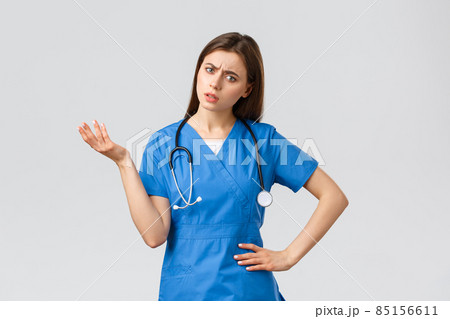 Healthcare workers, prevent virus, insurance and medicine concept. Confused and puzzled female nurse, doctor in scrubs with stethoscope, shrugging and lift hand, stare indecisive, cant understand 85156611