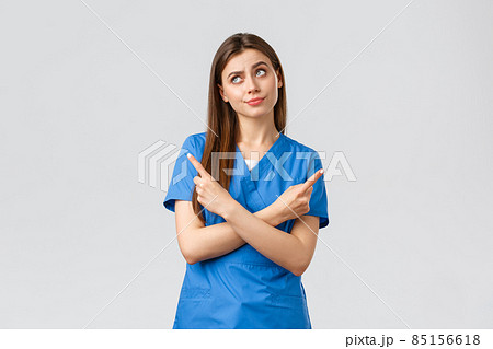 Healthcare workers, prevent virus, insurance and medicine concept. Nurse facing complicated choice. Doctor in blue scrubs, pointing sideways making tough decision, standing indecisive 85156618