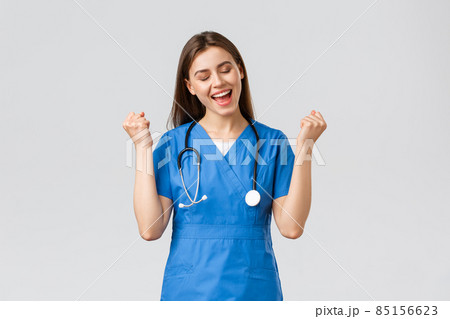 Medical workers, healthcare, covid-19 and vaccination concept. Happy cheerful female nurse, pretty enthusiastic doctor in blue scrubs, passed test, fist pump in rejoice, smiling relieved 85156623