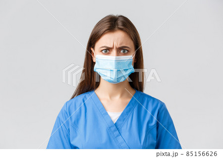 Covid-19, preventing virus, health, healthcare workers and quarantine concept. Angry or frustrated female nurse reacting to bad news. Doctor in blue scrubs and medical mask frowning disappointed 85156626