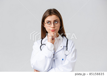 Healthcare workers, medicine, insurance and covid-19 pandemic concept. Concerned unsure young female doctor making serious decision, smirk look up thoughtful, smirk displeased, thinking tough choice 85156635