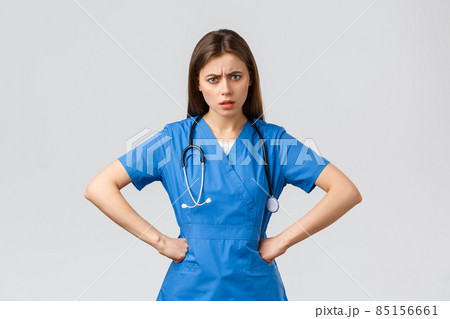 Healthcare workers, prevent virus, insurance and medicine concept. Angry and frustrated female nurse, doctor in scrubs, hold hands on waist and staring questioned camera, need explanation 85156661