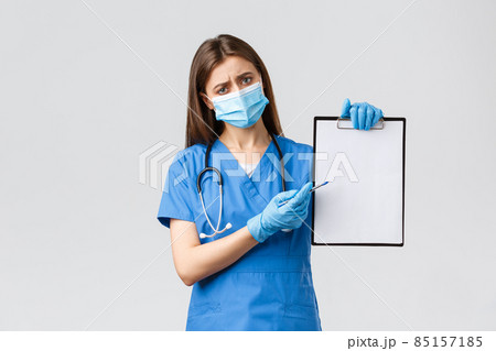 Covid-19, preventing virus, healthcare workers and quarantine concept. Tired concerned female nurse or doctor in blue scrubs, medical mask, explain importance use masks and gloves during coronavirus 85157185