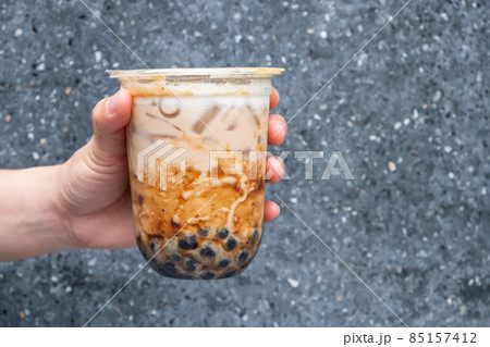 Cropped shot of someone hand holding a cup of iced Bubble milk tea. Bubble tea was a traditional drink in Taiwan before it became hugely popular all over the world. 85157412