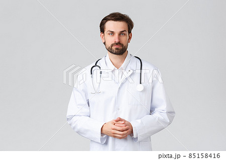 Hospital, healthcare workers, covid-19 treatment concept. Young doctor in scrubs making daily errands clinic, listening to patient symptoms, look camera, professional physician curing diseases 85158416