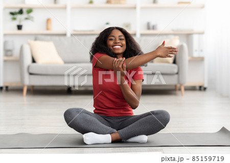 Happy athletic black woman stretching her body at home Happy athletic black woman stretching her body at home 85159719