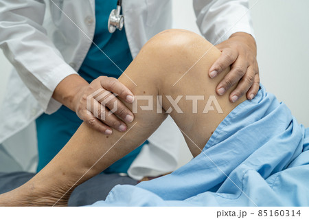 Asian doctor physiotherapist examining, massaging and treatment knee and leg of senior patient in orthopedist medical clinic nurse hospital. Asian doctor physiotherapist examining, massaging and treatment knee and leg of senior patient in orthopedist medical clinic nurse hospital. 85160314