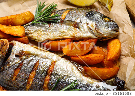 Delicious roasted fish and potatoes on parchment paper, closeup Delicious roasted fish and potatoes on parchment paper, closeup 85161688