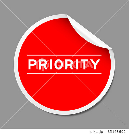 Red color peel sticker label with word priority on gray background 85163692