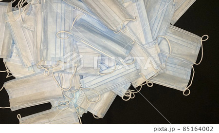 Medical masks in large numbers are scattered on a black table Medical masks in large numbers are scattered on a black table 85164002