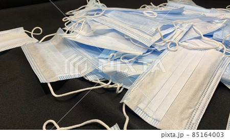 Medical masks in large numbers are scattered on a black table 85164003