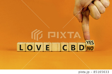Love CBD, cannabidiol symbol. Doctor turns a cube and changes words 'love CBD no' to 'Love CBD yes'. Beautiful orange background, copy space. Medical and love CBD cannabidiol concept. 85165633