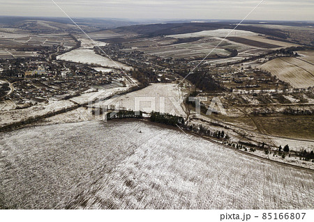 Top view of empty snowy fields and woody hills on cloudy sky background. Aerial drone photography, winter landscape. 85166807