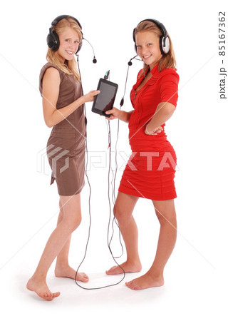 Two pretty teenage girls listening music on her headphones Two pretty teenage girls listening music on her headphones 85167362