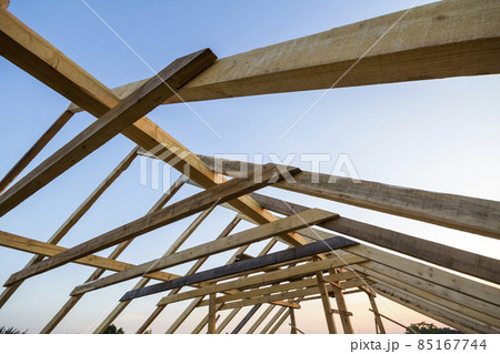 New wooden house under construction. Close-up of attic roof frame against clear sky from inside. Ecological dream home of natural materials. Building, construction and renovation concept. 85167744