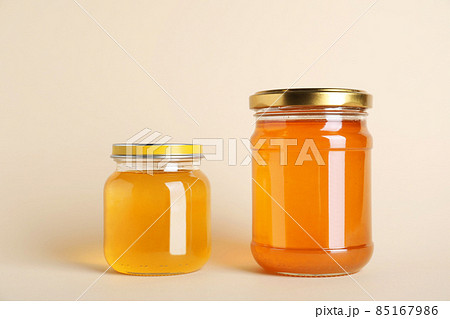 Jars with different types of organic honey on beige background Jars with different types of organic honey on beige background 85167986