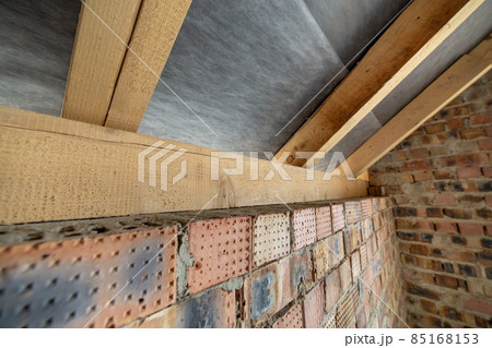 Interior of unfinished brick house with concrete floor, bare walls ready for plastering and wooden roofing frame attic under construction. Interior of unfinished brick house with concrete floor, bare walls ready for plastering and wooden roofing frame attic under construction. 85168153