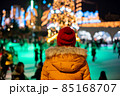 women looking at people skating on ice rink near Christmas tree garland lights 85168707
