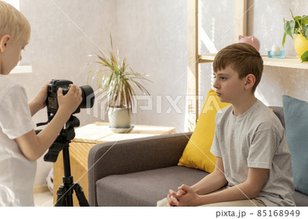 Children friends record videos on camera in the Livingroom. Teenage boy takes vlog. Child blogger. Children friends record videos on camera in the Livingroom. Teenage boy takes vlog. Child blogger. 85168949