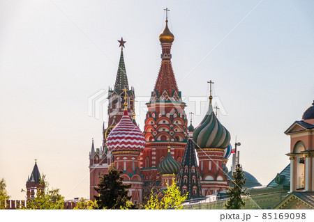 Multi-colored domes of St. Basil's Cathedral and the Spasskaya Tower of the Moscow Kremlin around the trees. Symbols of the Russian state. 85169098