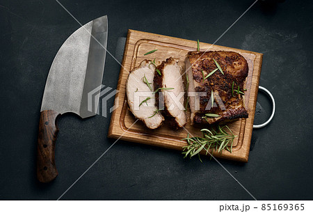 baked piece of pork meat in spices on a wooden board, cut into pieces baked piece of pork meat in spices on a wooden board, cut into pieces 85169365
