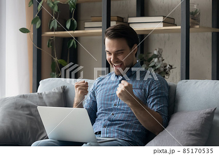 Man sit on sofa with laptop get news celebrate success Man sit on sofa with laptop get news celebrate success 85170535
