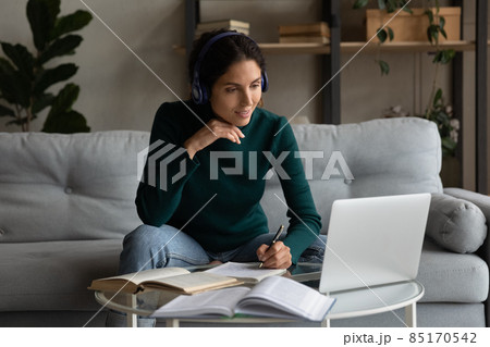 Latin woman in earphones study online on laptop 85170542