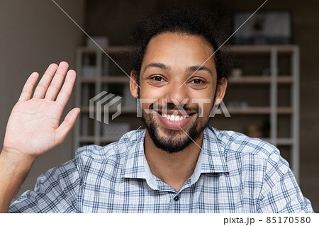 Closeup smiling African guy wave hand start videocall webcam view Closeup smiling African guy wave hand start videocall webcam view 85170580