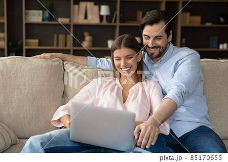 Joyful happy married couple relaxing at laptop on couch 85170655