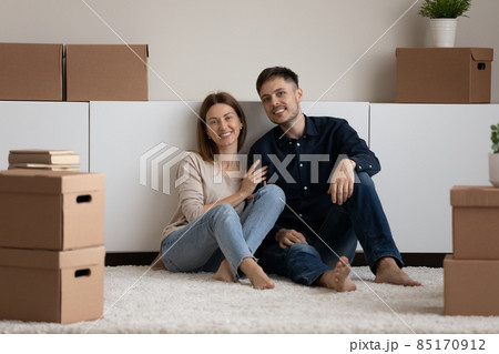 Portrait of happy young couple homeowners resting near carton boxes. 85170912