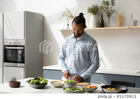 Happy young African American man cooking in modern kitchen. Happy young African American man cooking in modern kitchen. 85170913