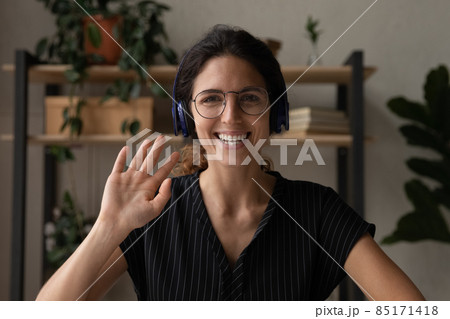 Millennial latin female in earphones talk to webcam wave hand Millennial latin female in earphones talk to webcam wave hand 85171418