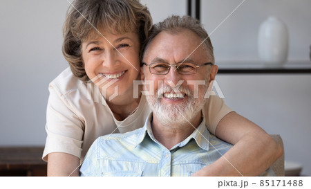 Happy husband and wife looking at camera with toothy smiles Happy husband and wife looking at camera with toothy smiles 85171488