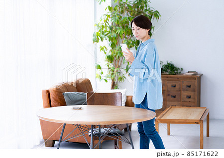 シックなリビングでコーヒーを飲みながらスマホを使うミドルの女性 シックなリビングでコーヒーを飲みながらスマホを使うミドルの女性 85171622