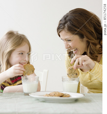 Mother and daughter dunking cookies in milk Mother and daughter dunking cookies in milk 85174258