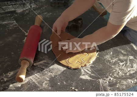 Hands dough and a rolling pin close-up boy helps mom in the kitchen make cookies 85175524