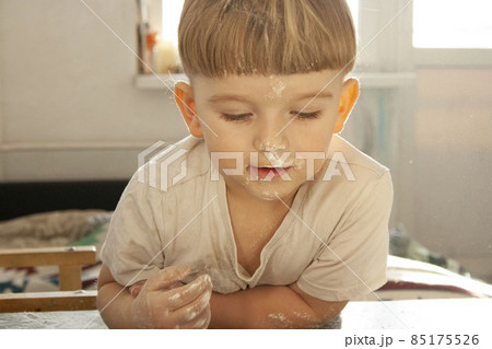 Portrait of a little boy of European appearance face stained with flour homemade cakes 85175526