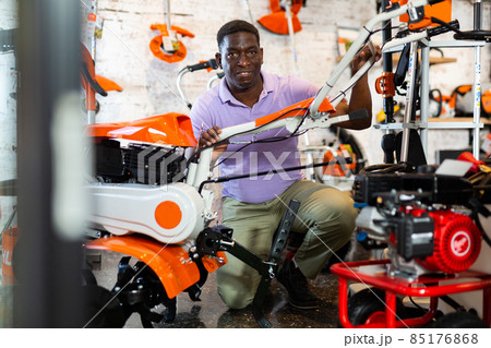 Average customer carefully selects new cultivator at garden tool store Average customer carefully selects new cultivator at garden tool store 85176868