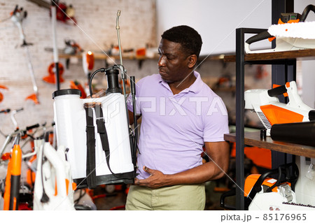 Man choosing shoulder sprayer in gardening tools store Man choosing shoulder sprayer in gardening tools store 85176965