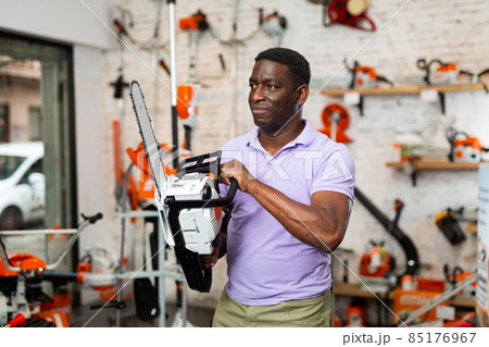 Man choosing chainsaw in gardening tools store 85176967
