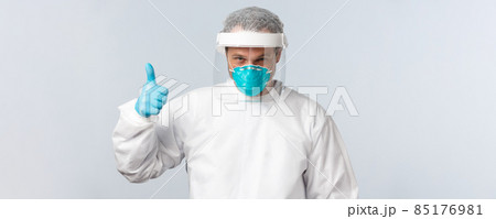Covid-19, virus, healthcare workers and vaccination concept. Determined and self-assured doctor in protective equipment and medical respirator show thumb-up, ready to examine contaigned patient 85176981