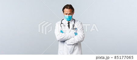 Covid-19, preventing virus, healthcare workers and vaccination concept. Offended timid doctor in medical mask and gloves looking insulted and upset, cross hands chest and frowning gloomy Covid-19, preventing virus, healthcare workers and vaccination concept. Offended timid doctor in medical mask and gloves looking insulted and upset, cross hands chest and frowning gloomy 85177065