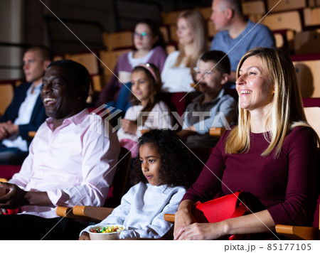 caucasian mother, african father and their children sitting at movie in auditorium 85177105