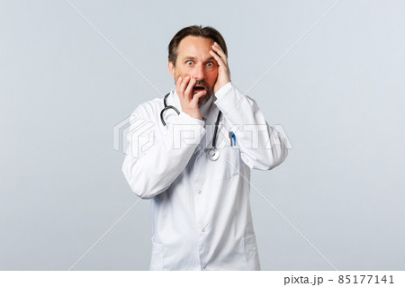 Covid-19, coronavirus outbreak, healthcare workers and pandemic concept. Shocked and worried male doctor in white coat, gasping, looking scared with panic at camera Covid-19, coronavirus outbreak, healthcare workers and pandemic concept. Shocked and worried male doctor in white coat, gasping, looking scared with panic at camera 85177141